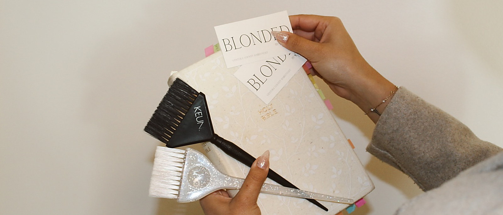Two tint brushes and a pair of her cards, held over a tabbed planner
